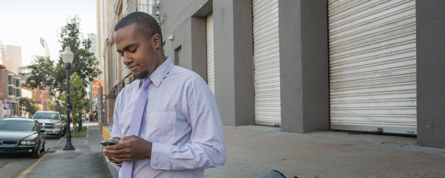 Business man standing near a loading dock looking at his phone